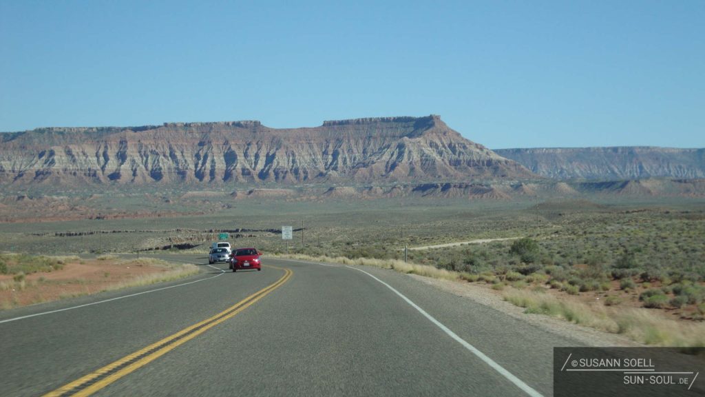 Straße, die zum Zion National Park führt. Rundherum Einöde und gewaltige Felsmassive in der Ferne.