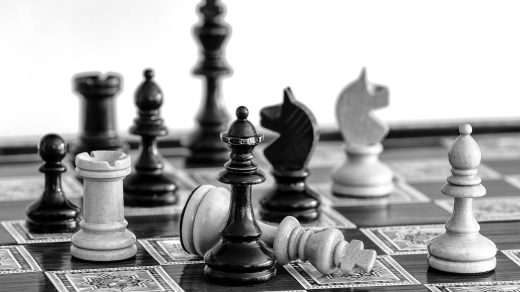 Schachspiel, bei dem der König schachmatt umgekippt auf dem Spielbrett liegt.